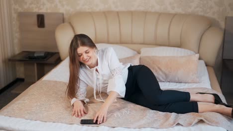 stylishly dressed young woman listens to music while lying in bed