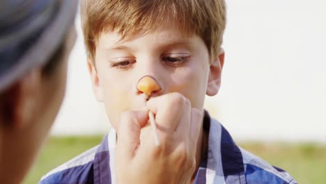 woman applying paint on boy nose 4k