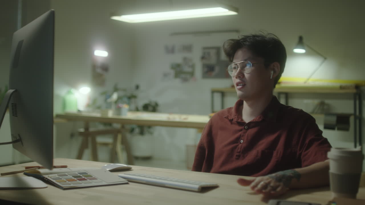 Young man on a video call at his desk in a creative office