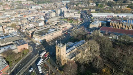 cinematic aerial footage of a small town in england showing church industrial areas, and busy town with traffic and roads