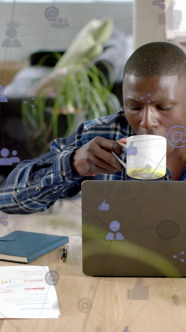 Video verticale: Uomo al laptop che guarda in basso, prende la tazza per bere un sorso mentre le icone dei social media fluttuano.
