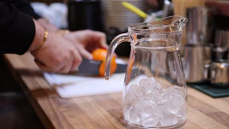 Bartender-cutting-up-orange-while-making-tropical-lemonade-in-the-pitcher