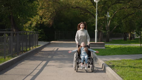 happy mother pushes daughter in wheelchair running in park