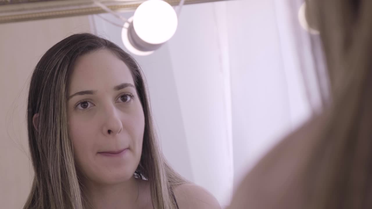 primo piano della giovane donna che mette il rossetto davanti allo specchio