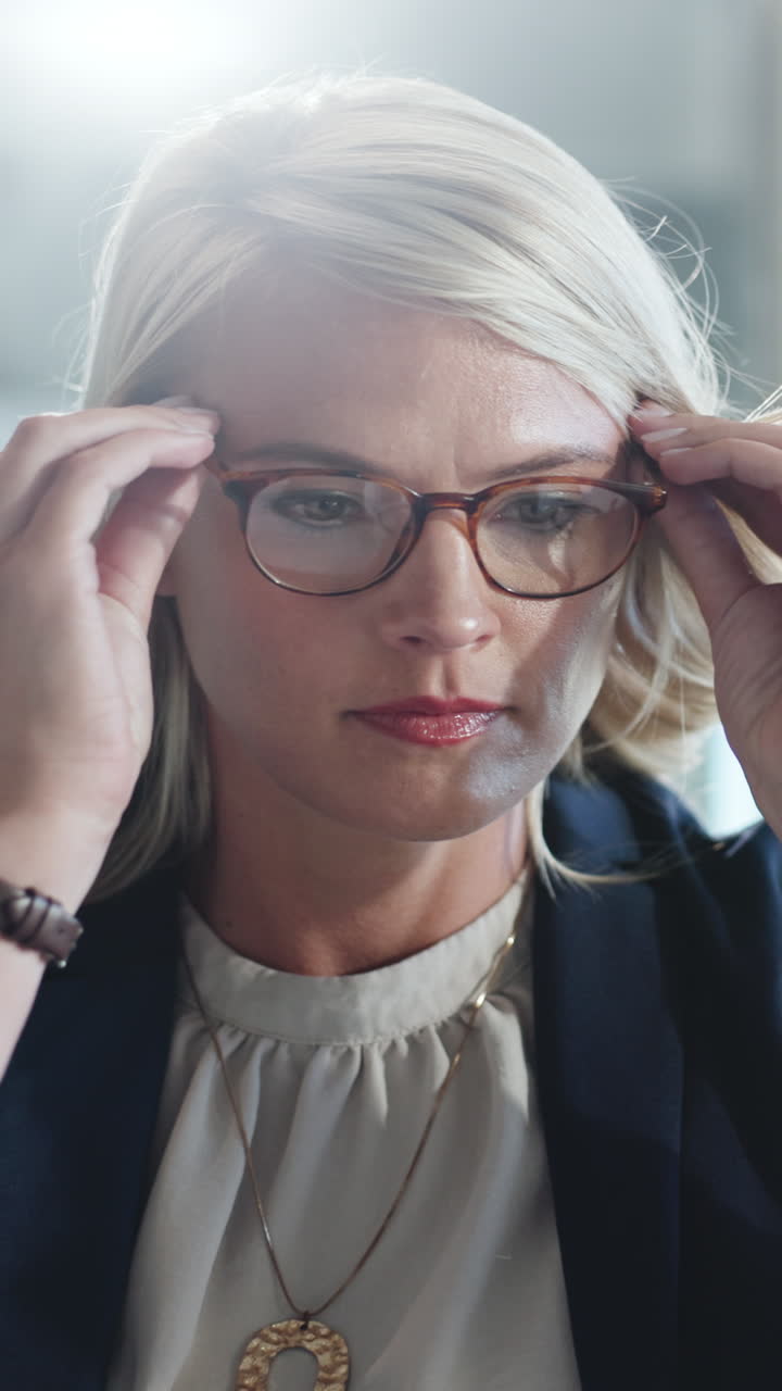 Donna d'affari bionda che si mette gli occhiali e si concentra