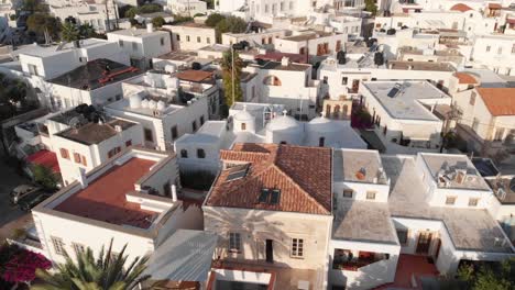 Ciudad-De-Patmos-Grecia-En-Las-Islas-Griegas-Pueblo-Histórico-Drone-Vista-Aérea-Palmeras-Y-Edificios-Blancos-Con-Colinas-Y-El-Océano-Detrás