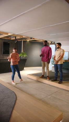 vertical video: presenting ideas, woman speaking to two colleagues in modern office setting