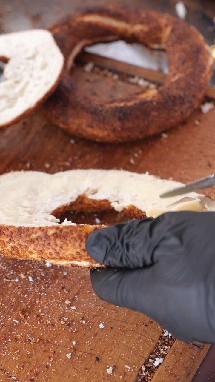 Hand Spreading Butter on a Freshly Sliced Simit