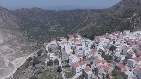 bird's eye view revealing the beauty of nikia village, island nisyros, greece - drone footage of the settlement and volcanic caldera behind it.