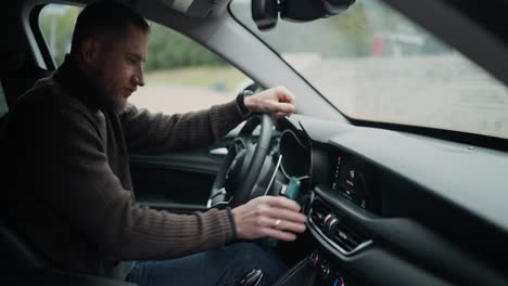 man driving a car, using a phone and car stereo