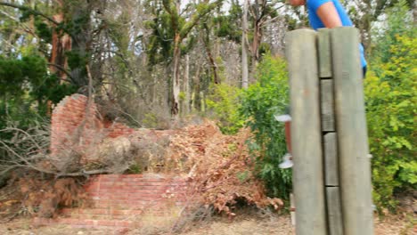 Hombre-Y-Mujer-Aptos-Para-Escalar-Una-Pared-De-Madera-Durante-La-Carrera-De-Obstáculos