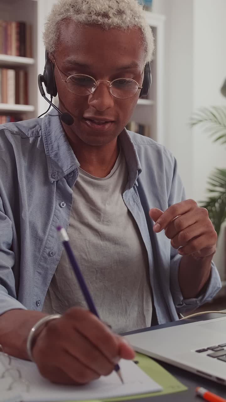 Young positive african american man uses headset and laptop for video call