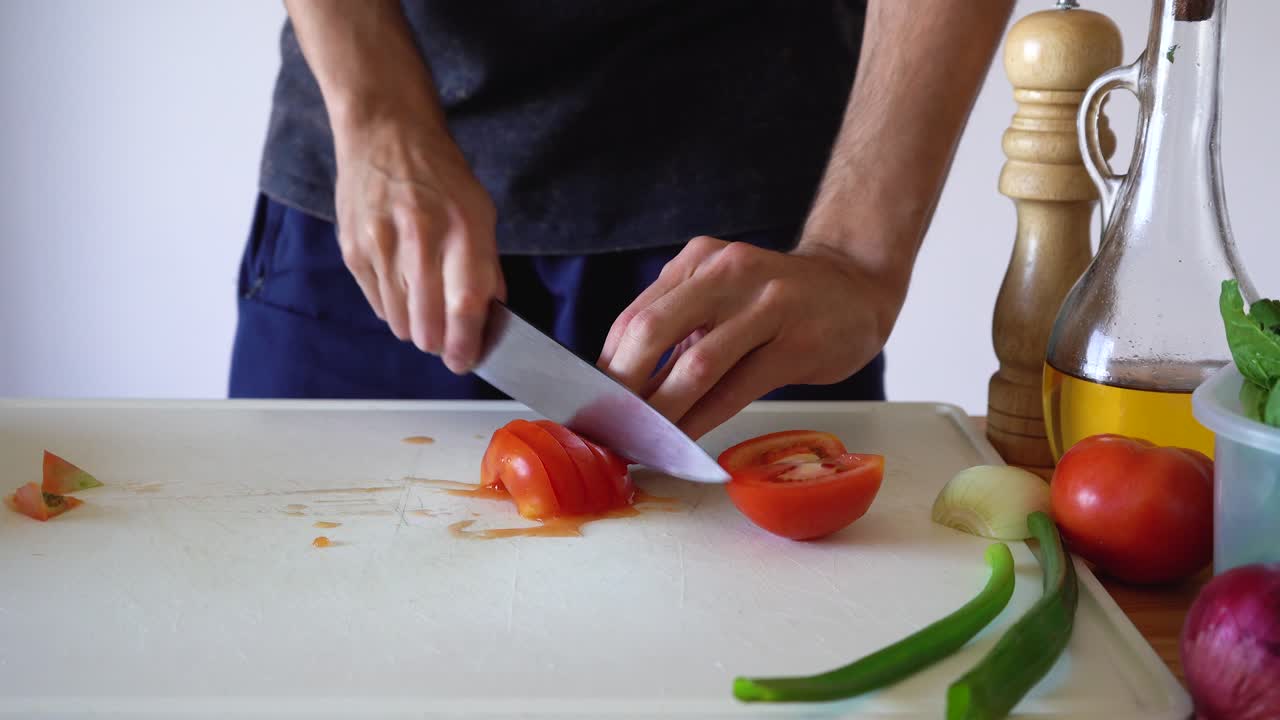 persona cortando tomate rojo fresco en una tabla de cortar blanca