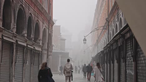 slow motion of people walking in the fog in venice close to the rialto bridge