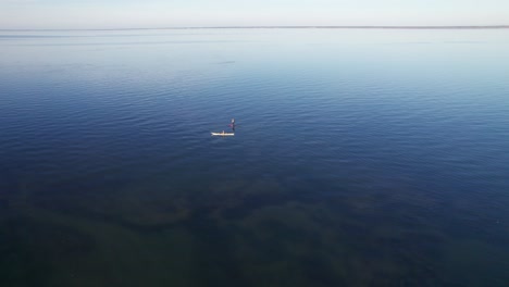 two people kayaking at sunset calm mirror-like sea golden hour