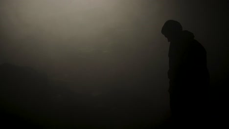 silhouette of a person in foggy mountains