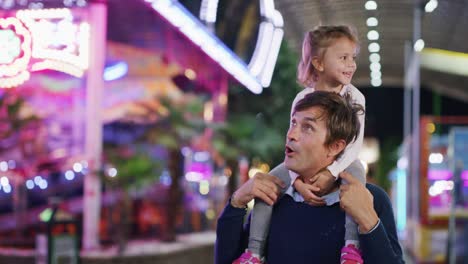 authentic shot of a happy smiling family is having fun together in amusement park with luna park lights at night.