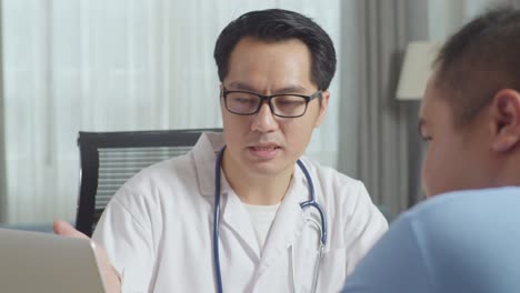 close up of asian male doctor with a fat male patient in clinic, sitting at desk and discussing about the results of medical check up on a laptop