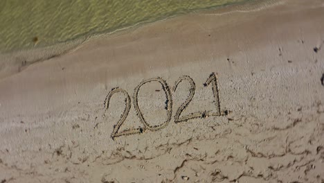 twenty twenty one written in the sand and spinning clockwise showing it as a crazy year