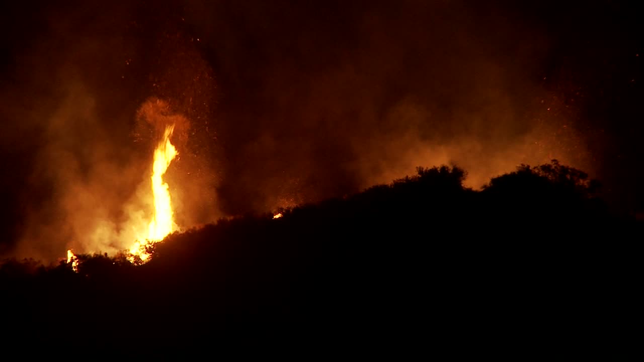 los bomberos luchan contra un furioso incendio forestal de california por la noche lanzando agua desde un camión cisterna aéreo