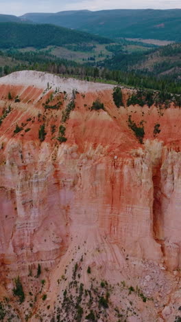 stunning huge rock of coral color in bryce national park. mountains overgrown with pine forest at backdrop. aerial view. vertical video