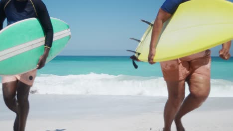 senior couple running with surfboards