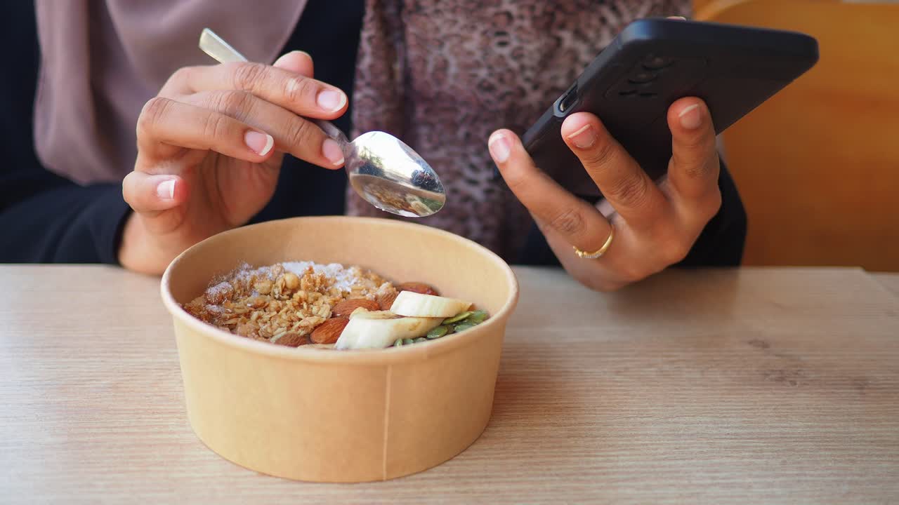 Woman enjoying a healthy breakfast while using her smartphone