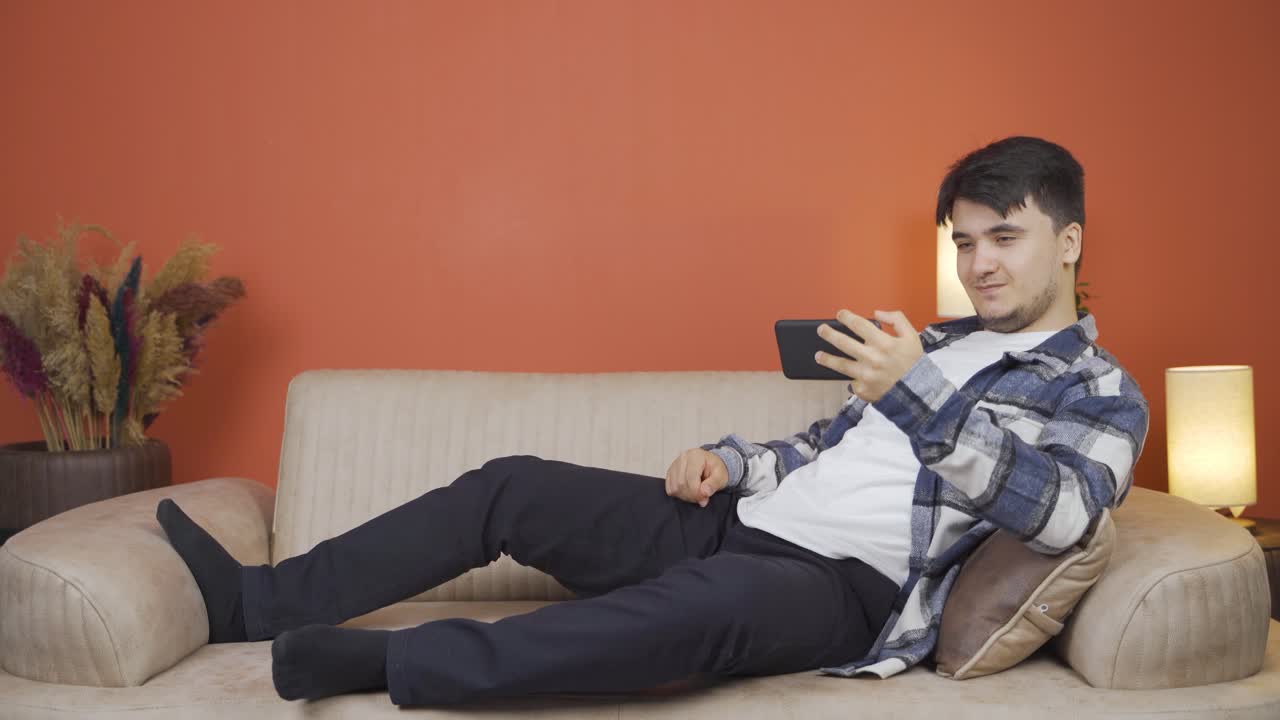 소파에 누워 있는 남자가 휴식을 취하고 있습니다.