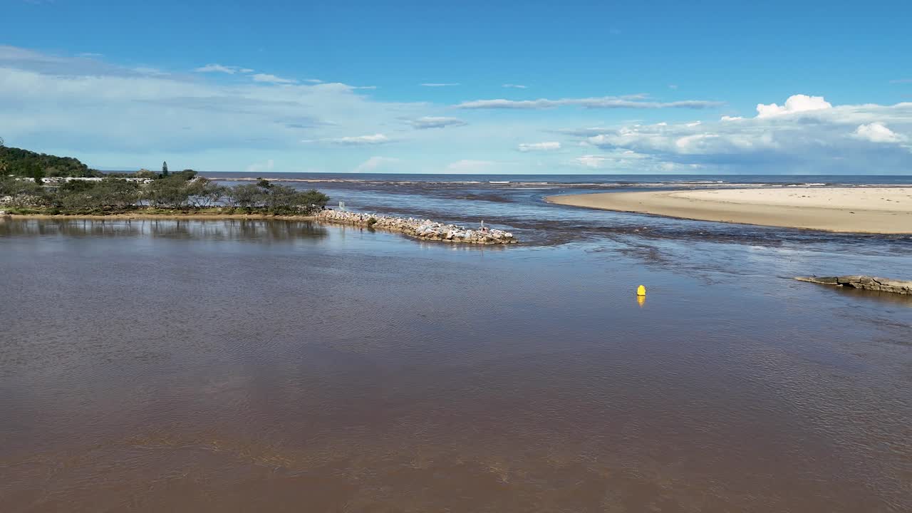 Yellow buoy drifting in calm Nambucca River estuary, sandy banks, wide landscape, bright daylight