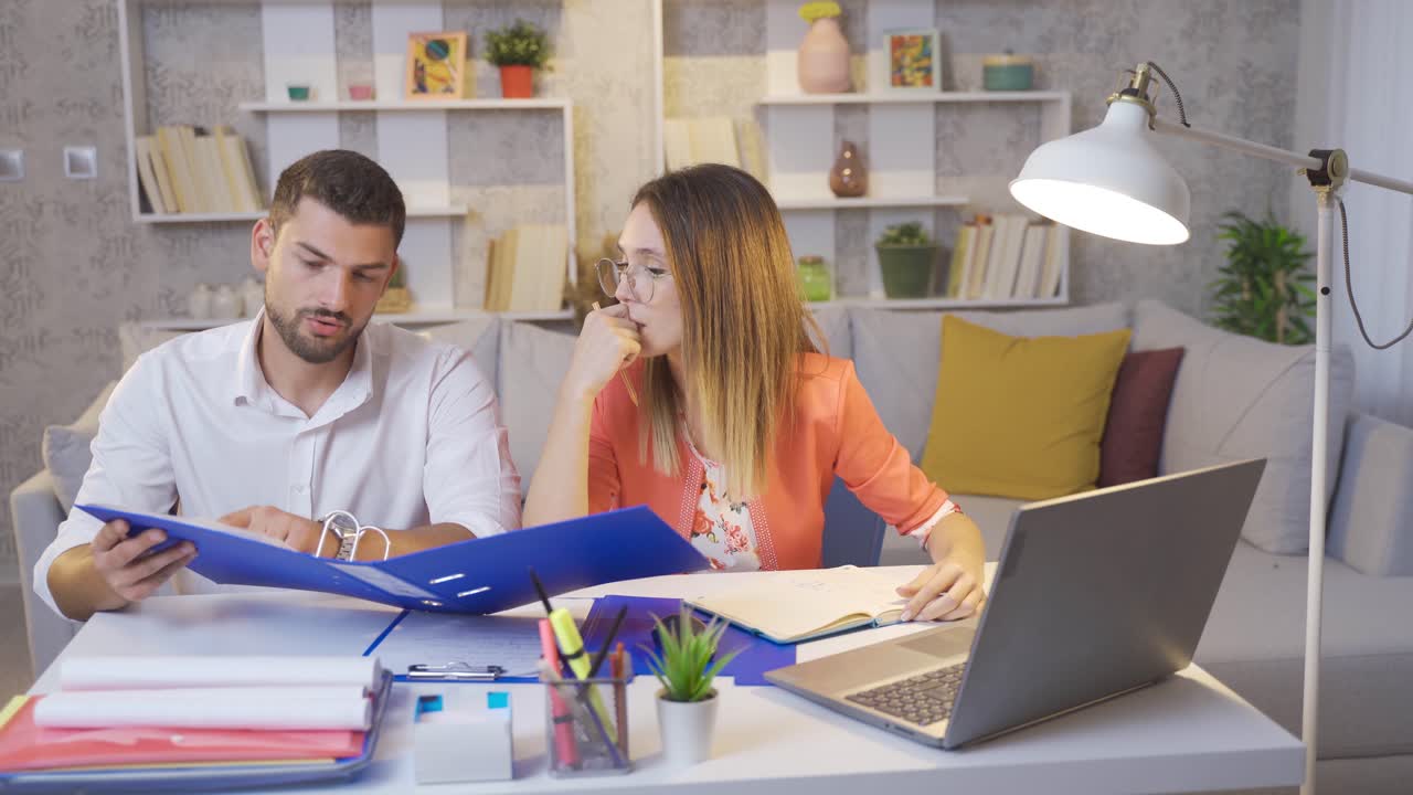 pareja casada trabajando en casa por la noche mirando archivos y computadora portátil.