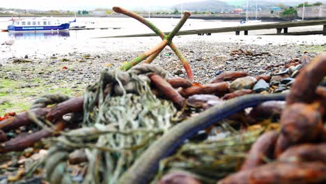 rusted algae covered anchor and chains on low tide welsh harbour seafront dolly left