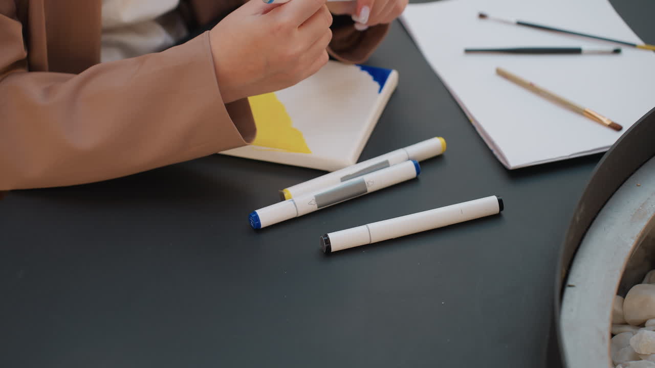 Individuos organizando metódicamente materiales y decidiendo combinaciones de colores; creadores organizando sistemáticamente rotuladores y lienzos mientras revisan bocetos y seleccionan tapas de colores.