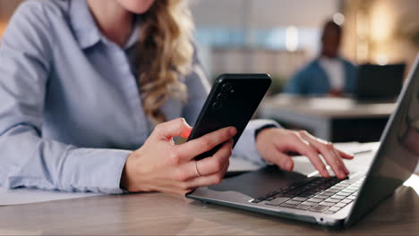 woman using a laptop and mobile phone in an office