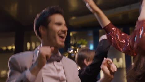 close up view of couple dressed in elegant clothes dance with friends at the new year's party