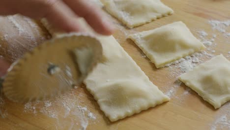 hands cutting ravioli pieces with fluted pastry wheel