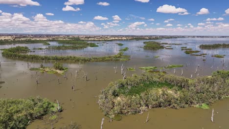 Kurze-Luftaufnahme-Der-Inseln-Im-Lake-Mulwala,-New-South-Wales,-Australien-Und-Flauschiger-Wolken-Und-Ackerland-Dahinter