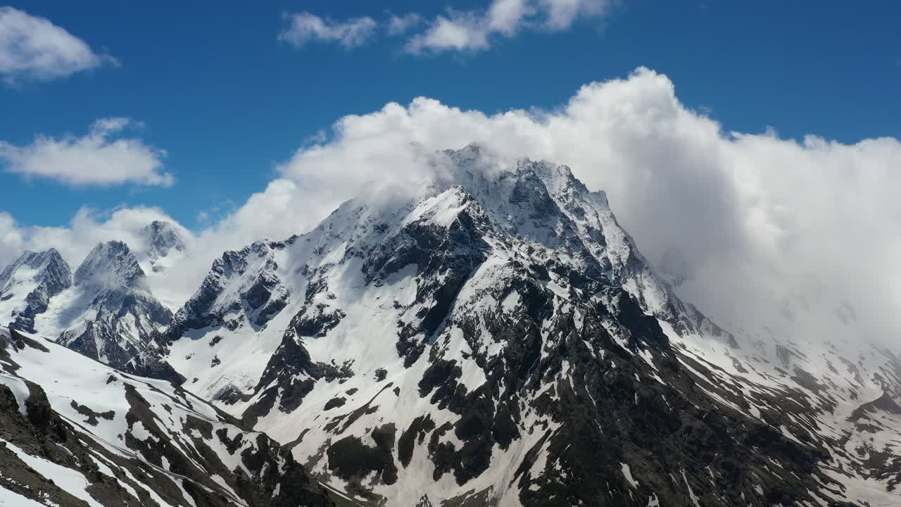 눈 덮인 아름다운 산봉우리와 빙하 위로 산 구름을 통과하는 항공 비행.