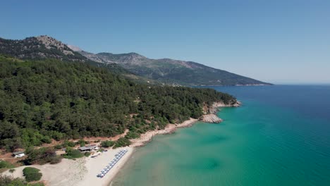 circular orbit aerial reveal of paradise beach with turquoise water, surrounded by green vegetation and high mountain peaks, thassos island, greece, europe