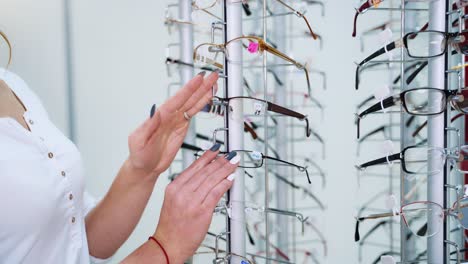 eyeglasses shop. stand with glasses in the store of optics. woman's hand chooses glasses.