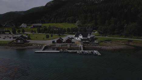 aerial view of norwegian cabins with boats moored on marina in nordland, norway. - pull back, tilt up