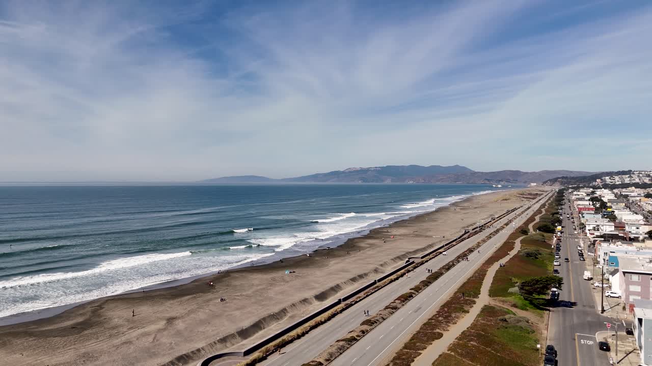 High-angle shot of Ocean Beachâ€™s shoreline, San Francisco homes, and the iconic Cliff House area with coastal hills in the background.