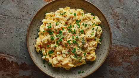 deliciosos huevos revueltos en un plato de cerámica adornados con hierbas