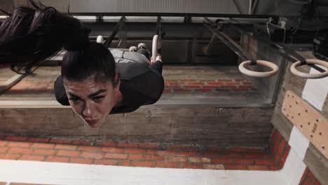 young woman doing a ring pull-up in the gym