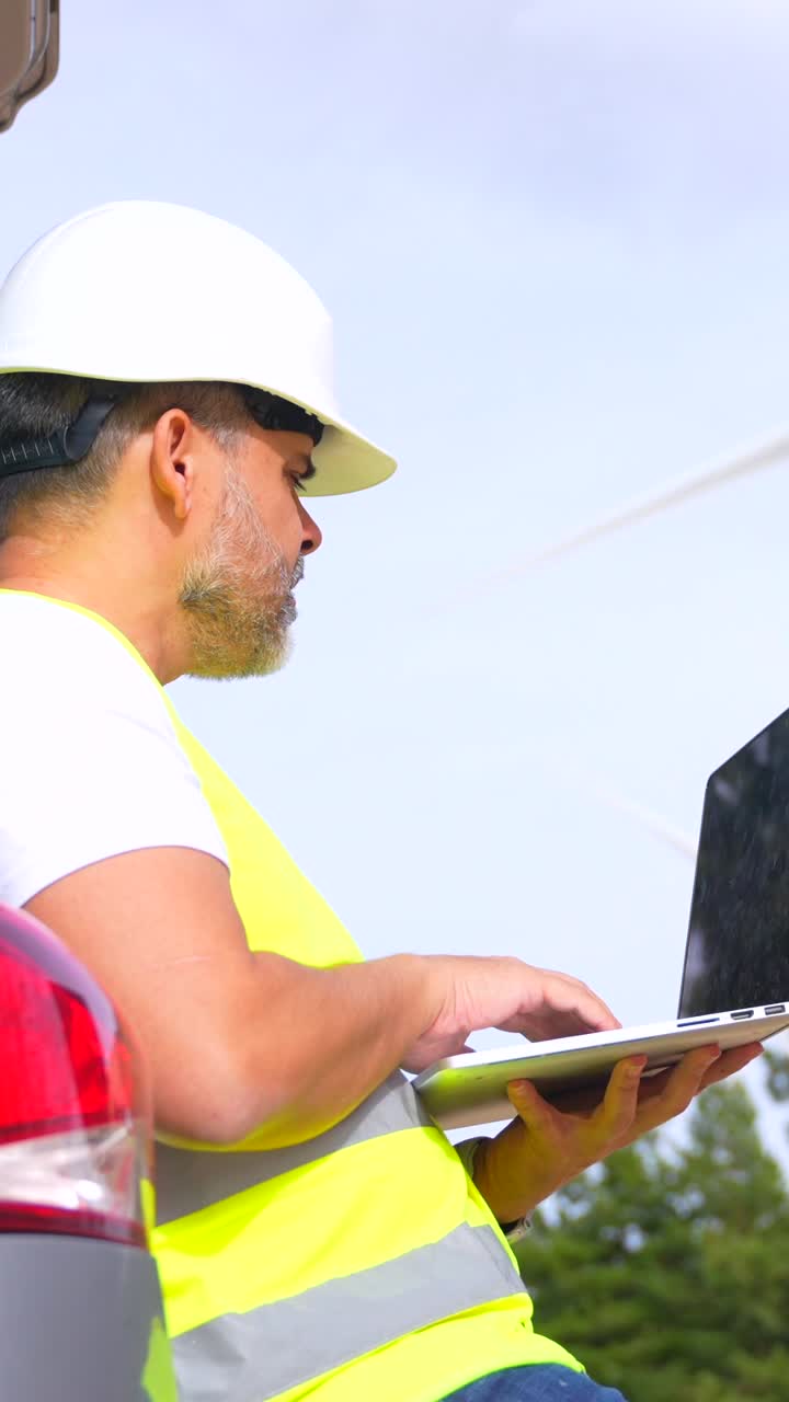 Engineer working on a laptop near a wind turbine