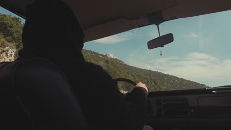 person driving a vintage car on a scenic mountain road