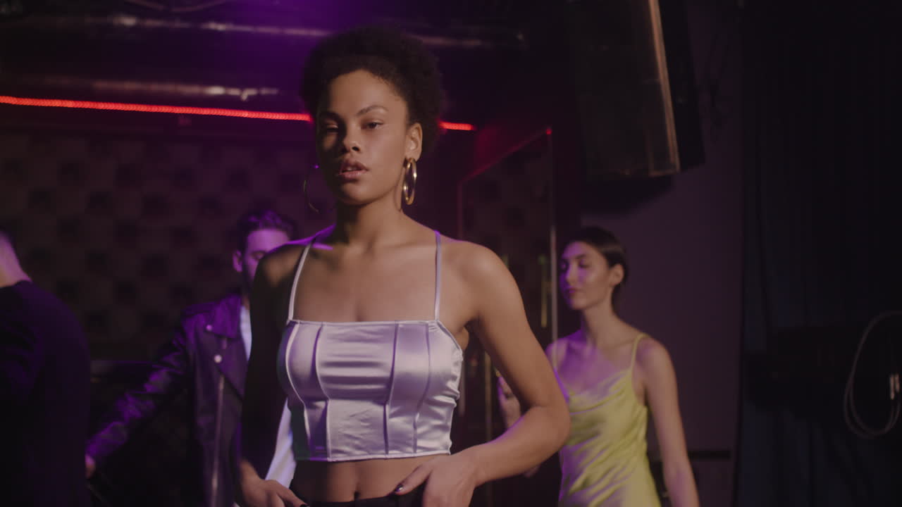 Portrait Of Beautiful Girl Looking Confident At Camera At Disco While Her Friends Dancing Behind Her 3