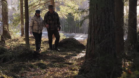 Two-seniors-enjoying-a-leisurely-walk-in-a-sunlit-pine-forest,-companionship-in-nature