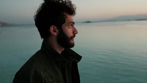 profile shot of depressed man next to lake at sunset looking up in desperation