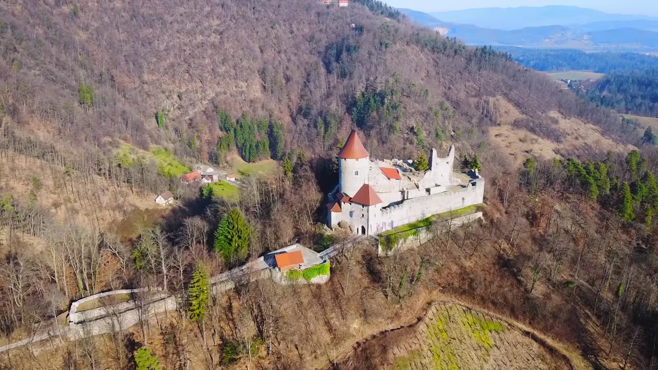 Pohled z ptačí perspektivy na hrad Žovnek, Braslovče, Slovinsko, který se nachází nad jezerem Žovnek uprostřed husté zeleně. Letecký snímek