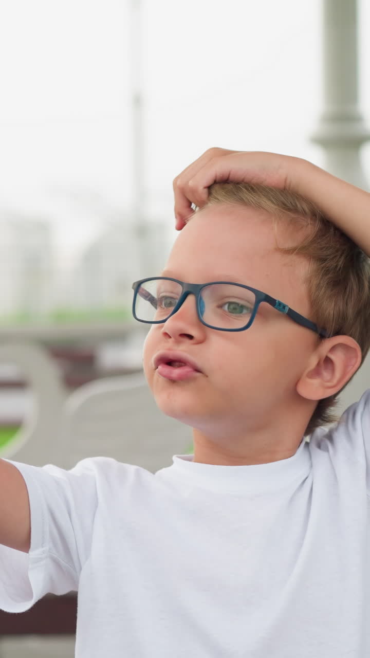 un niño con gafas señala juguetón algo en la distancia mientras está de pie al aire libre